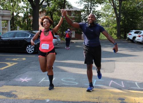 Two athletes hold hands as they cross the finish line of the mock race on the last day of training